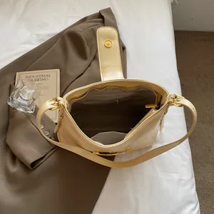 Top view of beige bucket bag showing magnetic clasp and interior zip pocket on white bed