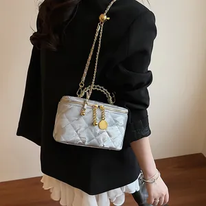 Détail du sac boîte argenté matelassé avec chaîne dorée et boule en métal réglable