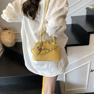 Détail du sac à main jaune vif en cuir grainé avec pendentif en forme de coeur
