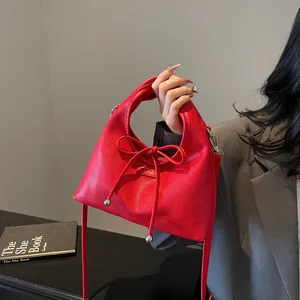 Detail of red lychee grain leather handbag featuring iconic bow tie and silver hardware