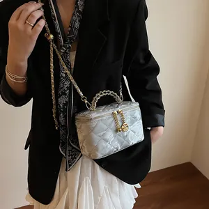Détail du sac boîte matelassé argenté avec pendentif rose dorée et bandoulière