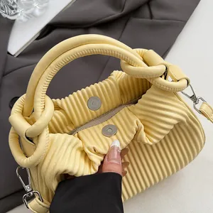 Gros plan détaillé du sac à main plissé jaune clair avec boucle magnétique et détails argentés