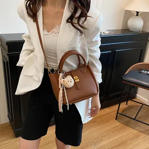 Gros plan d'un sac seau marron grainé avec boucle dorée et breloque ours en peluche