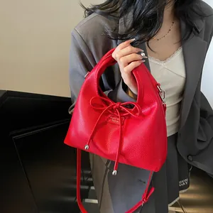 Close-up of red lychee leather handbag with bow detail and silver metal hardware