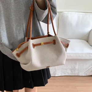 Detail of canvas tote bag showing drawstring closure, leather trim and gold metal logo