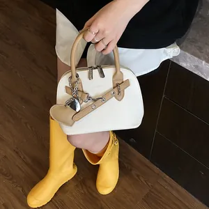 Détail du sac à main en cuir blanc avec poignées marron et pendentif en cœur