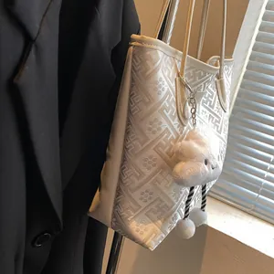 Dettaglio ricamo fiori di prugno e ciondolo a nuvola sulla borsa tote di grande capacità