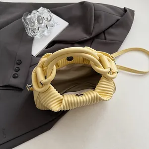 Vue détaillée du sac à main plissé jaune clair montrant le fermoir magnétique et l'intérieur