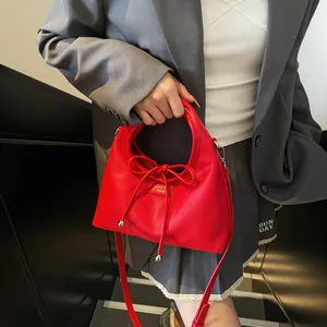 Detail of red lychee grain leather handbag with bow drawstring and adjustable strap