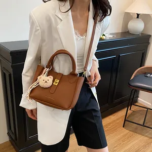 Détails du sac seau marron en cuir grainé avec fermoir doré et charme d'ours peluche