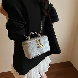 Détail du sac matelassé argenté avec pendentif camélia doré et texture métallique chic