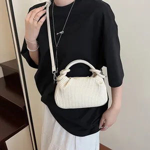 Détails de la texture plissée verticale et de la poignée nouée d'un sac à main crème