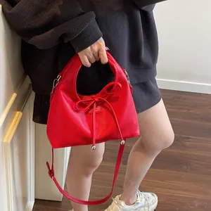 Detail of red leather handbag with lychee texture and elegant bow decoration on the front