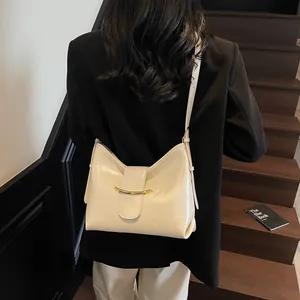Detail of cream PU leather bucket bag with gold metal buckle on a black blazer
