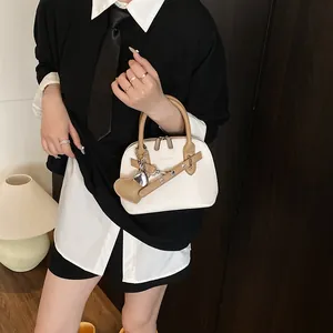Détail du sac à main blanc motif litchi avec poignées marron et breloque en cœur