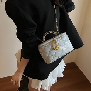Détail du sac de maquillage matelassé gris avec bandoulière chaîne dorée porté croisé