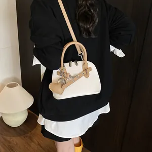 Sac coquillage blanc avec poignées marron et breloque cœur dans un intérieur douillet