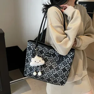 Dettaglio della grande borsa tote con motivo geometrico bianco e ciondolo a nuvola