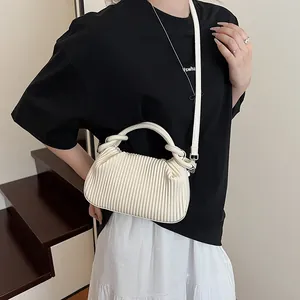 Vue détaillée de la texture plissée crème et des poignées torsadées de ce sac à bandoulière