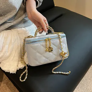 Détail d'un vanity bag bleu clair matelassé avec des pendentifs en forme de rose dorée