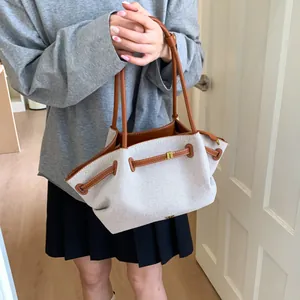 Detail of canvas tote bag with brown leather trim and golden metal zipper hardware