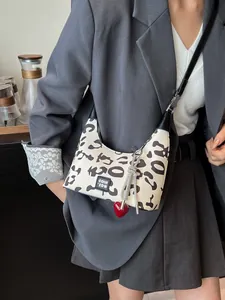 Leopard print crossbody bag with metal tassel and heart charm on a gray blazer outfit