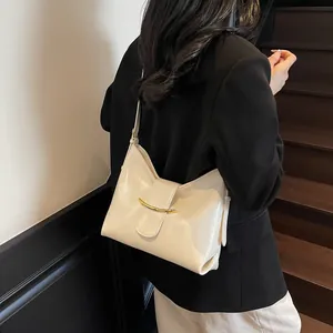 Detail of cream bucket bag with glossy leather texture and gold metal accent on strap