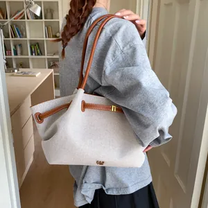Detailed side view of large canvas tote bag with brown leather straps and gold logo