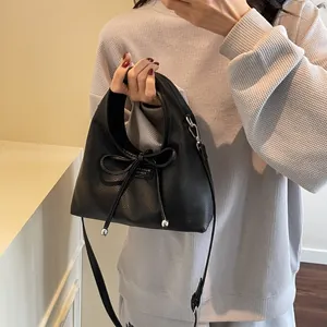 Detail of black pebbled leather handbag featuring a center bow and silver metal hardware