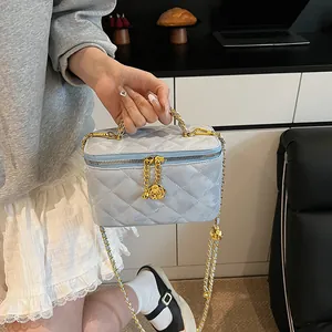 Détail du sac matelassé bleu clair avec chaîne dorée et pendentif rose élégant