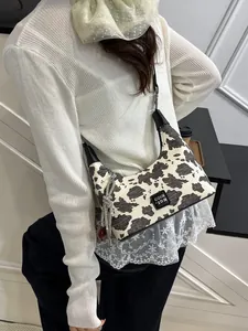 Stylish cow print crossbody bag for women featuring a chic silver bow charm detail