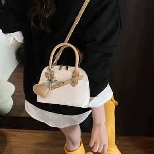 Détail du sac à bandoulière blanc crème avec pendentif cœur et texture litchi