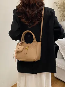 Sac seau beige texture lychee avec fermoir doré et breloque ours sur un modèle