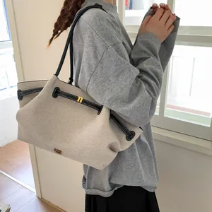 Detail of canvas tote bag with black leather straps and gold hardware on model