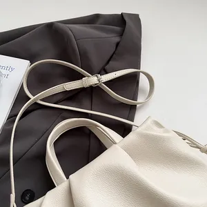 Detail of creamy white ruched tote bag showing pebbled leather texture and silver buckle