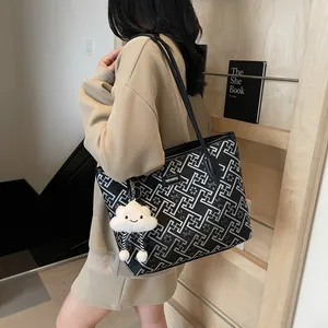 Dettaglio della grande borsa tote nera con motivo geometrico bianco e placca in metallo