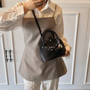 Détail du sac à main noir en cuir grainé avec finitions argentées et breloque coeur