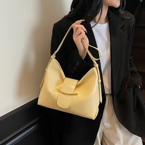 Close-up of creamy beige bucket bag showing shiny leather texture and gold buckle detail