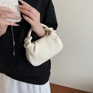 Détail du sac à main plissé blanc avec une poignée nouée et une texture plissée verticale