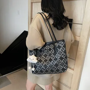 Dettaglio di una grande borsa tote con motivi geometrici e ciondolo a forma di nuvola
