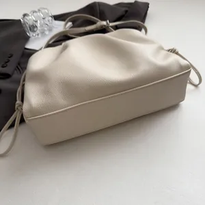 Close-up of ruched cloud bag in creamy beige PU leather with elegant knot strap detail