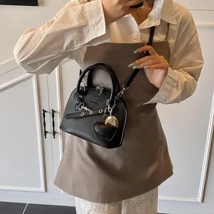 Détail d'un sac à main en cuir grainé noir avec boucles argentées et pendentif coeur
