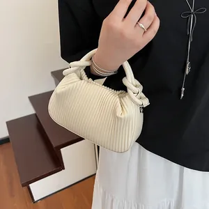 Détail d'un sac à main beige plissé avec texture verticale et poignée nouée tissée