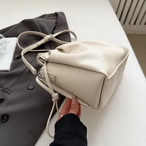 Detail of creamy white ruched tote bag showing pebbled leather texture and soft top folds