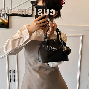 Détail du sac à main noir en cuir grainé avec mors argenté et pendentif coeur