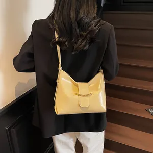 Detail of light yellow leather bucket bag with gold metal buckle on a shoulder strap