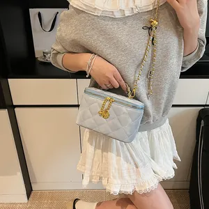 Gros plan sur le sac boîte matelassé bleu clair avec détails dorés et pendentif rose