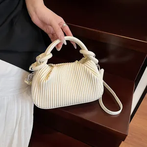 Détail du sac à main plissé crème avec poignée nouée sur des marches en bois