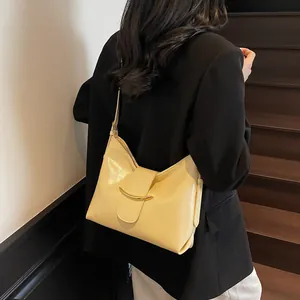 Detail of a bright yellow patent leather bucket bag with gold metal buckle decoration