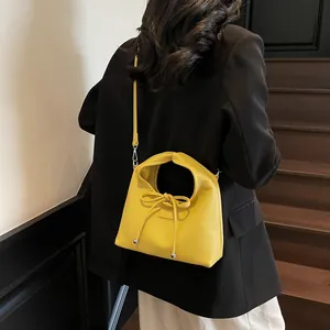 Detail view of bright yellow half-moon bag with lychee texture and bow detail